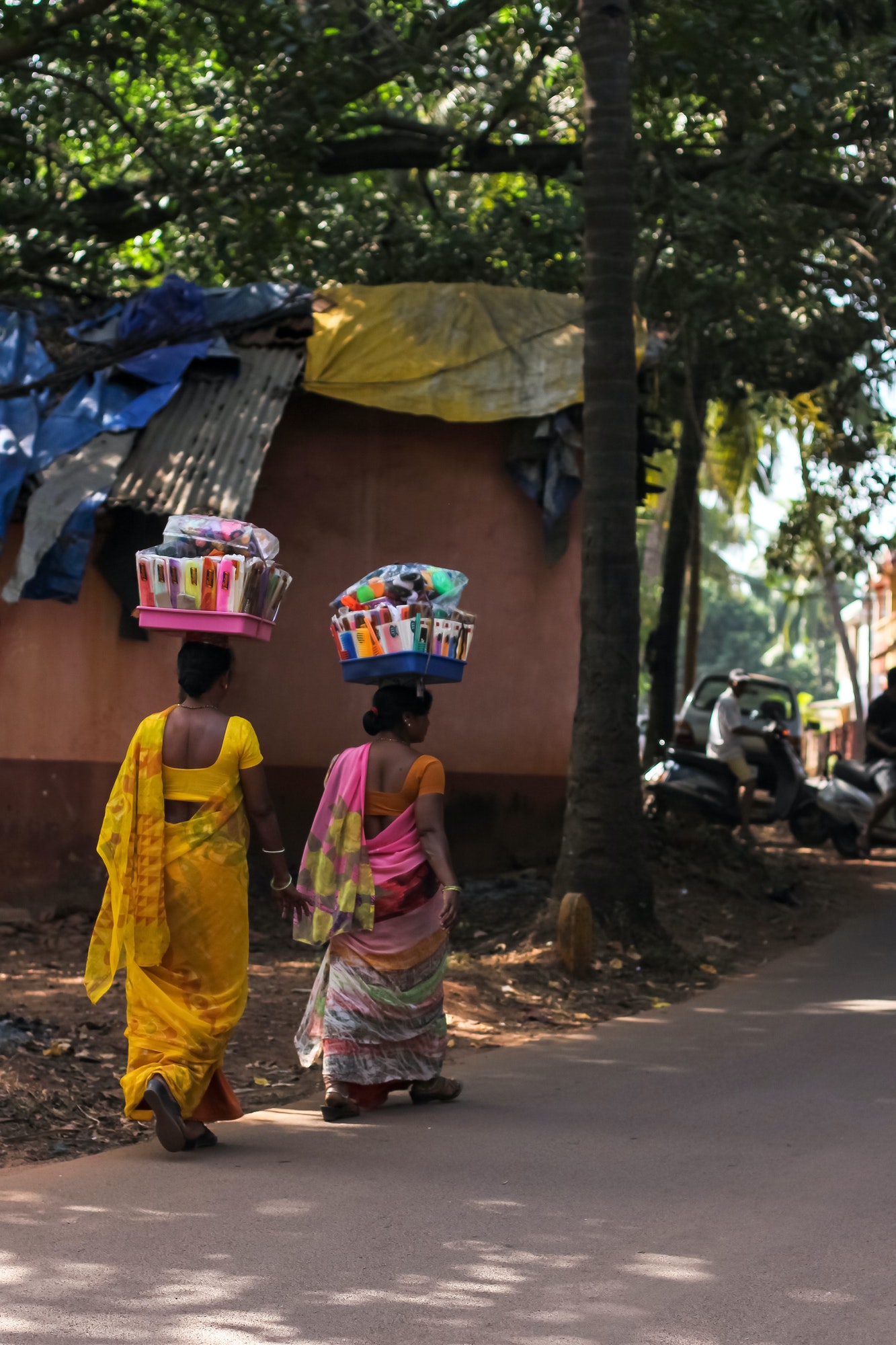 Indian women dressed in the traditional hindu dress - Sari carrying goods for sale on their heads.